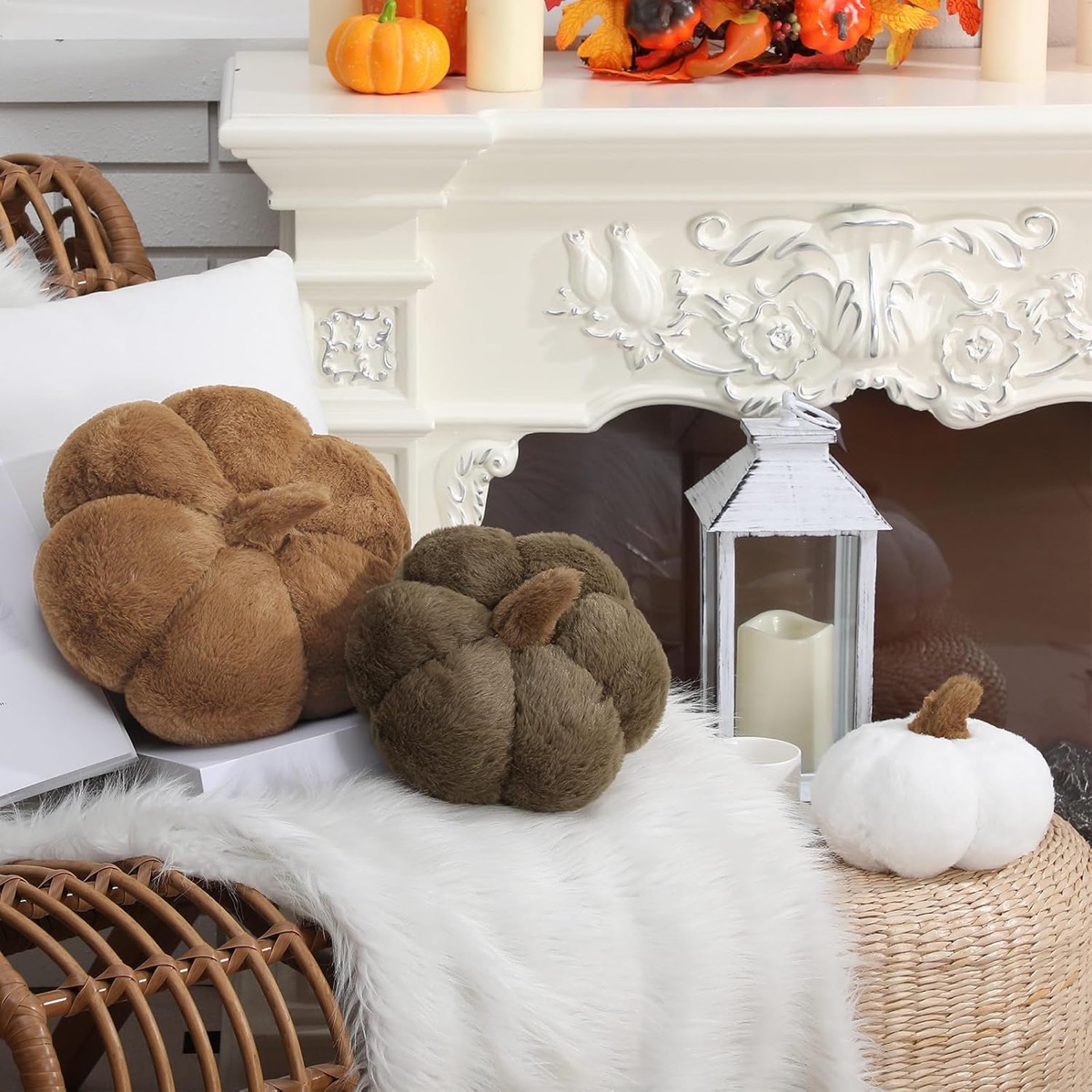Three plush pumpkin pillows in caramel, olive and cream on a rattan chair and pouf with a faux fur throw