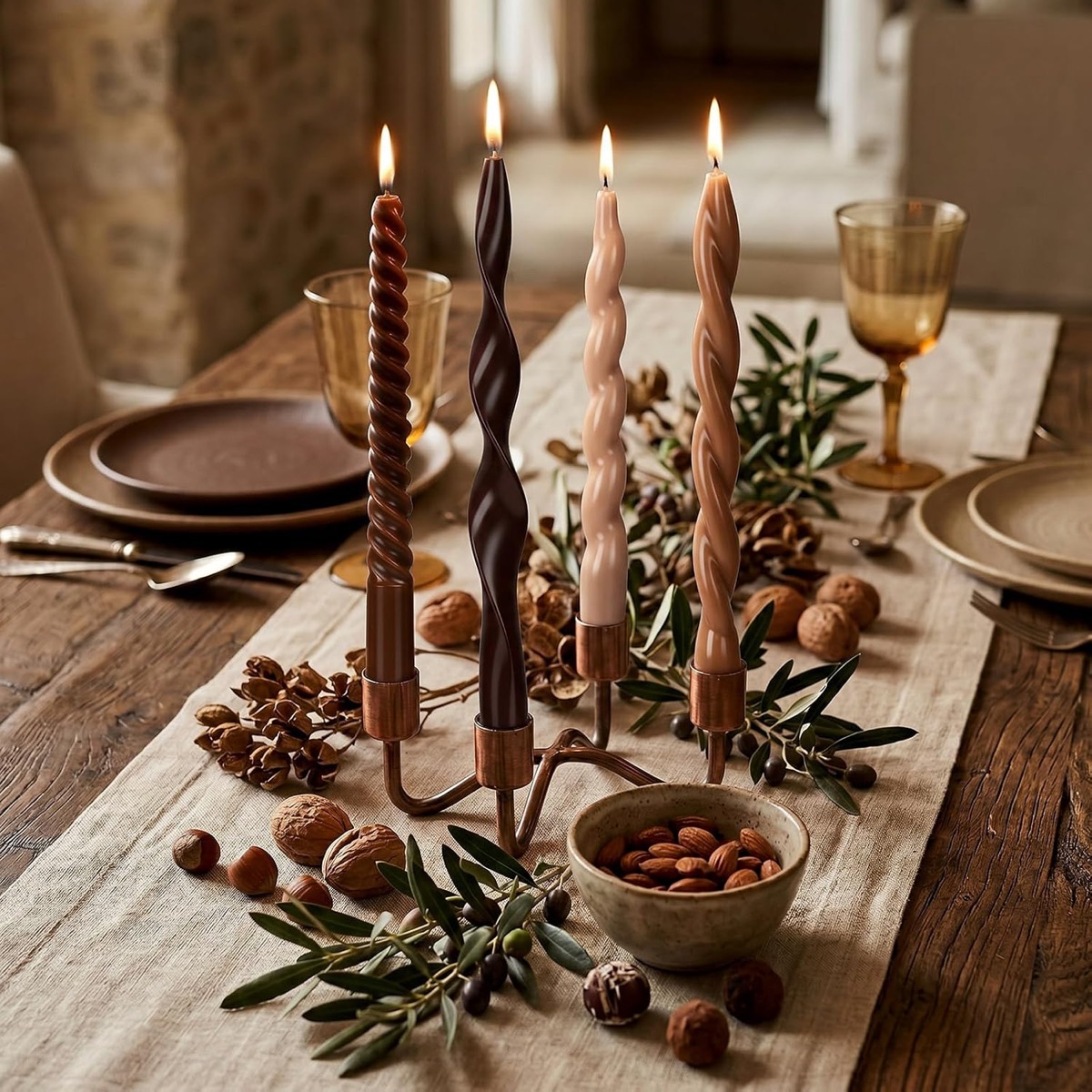 Lit spiral and twisted taper candles in brown, chocolate, cream and caramel on a candelabra over a linen table runner